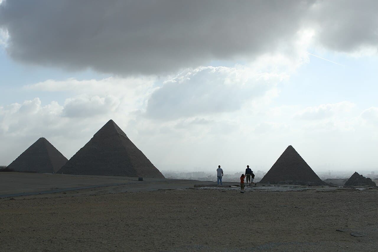 A family walking near the pyramids of Giza at dusk