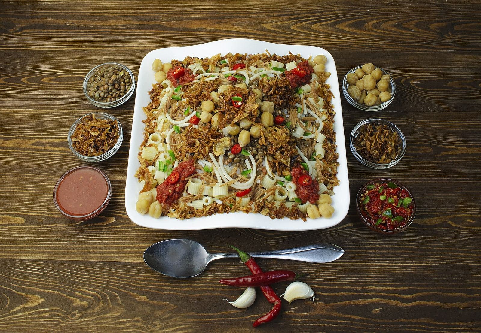 A plate of koshary, a popular Egyptian street food dish, with side condiments