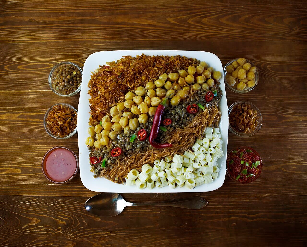 A shared Egyptian koshary platter with lentils, chickpeas, rice and pasta