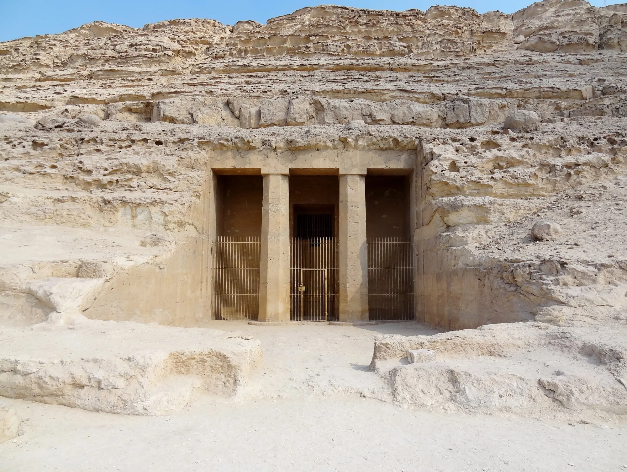 The rock-cut tomb entrance of Amenemhat (BH 2) at Beni Hasan, with its two columns and an iron gate
