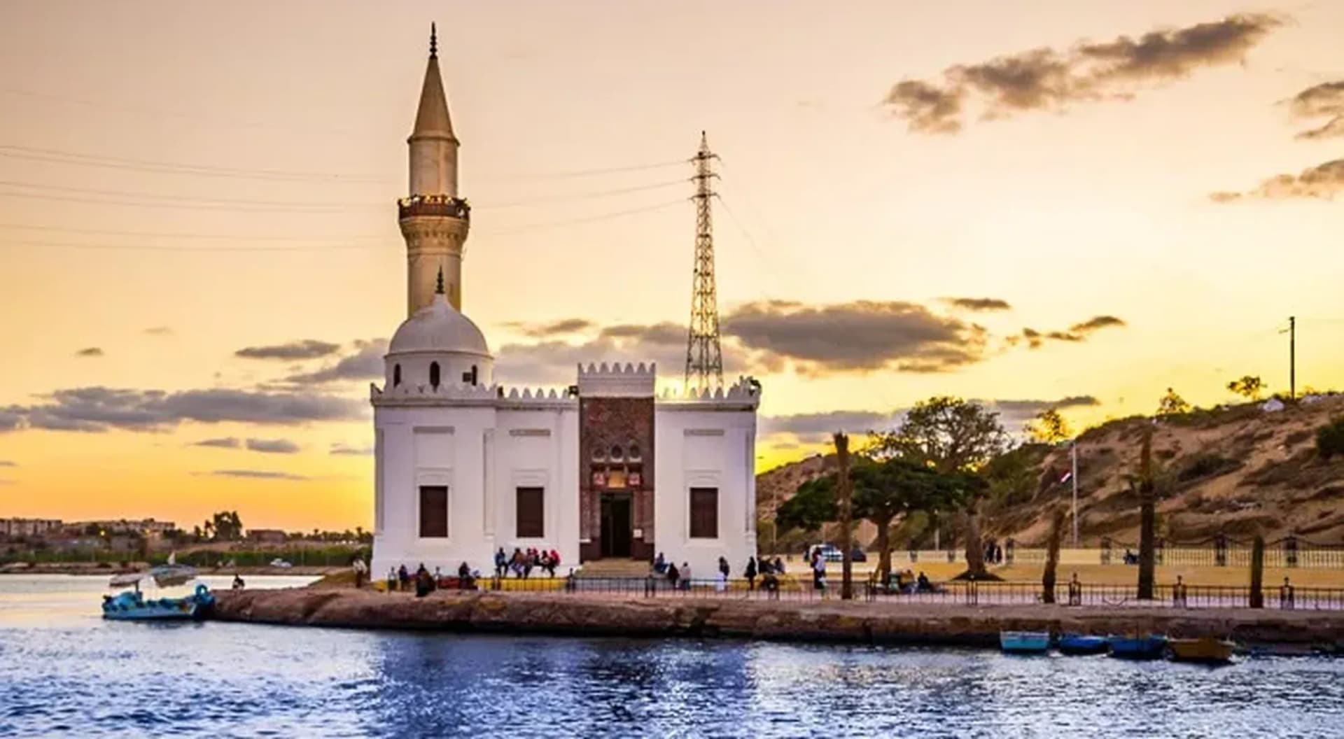 A white mosque with a tall minaret beside the river at Rosetta (Rashid)