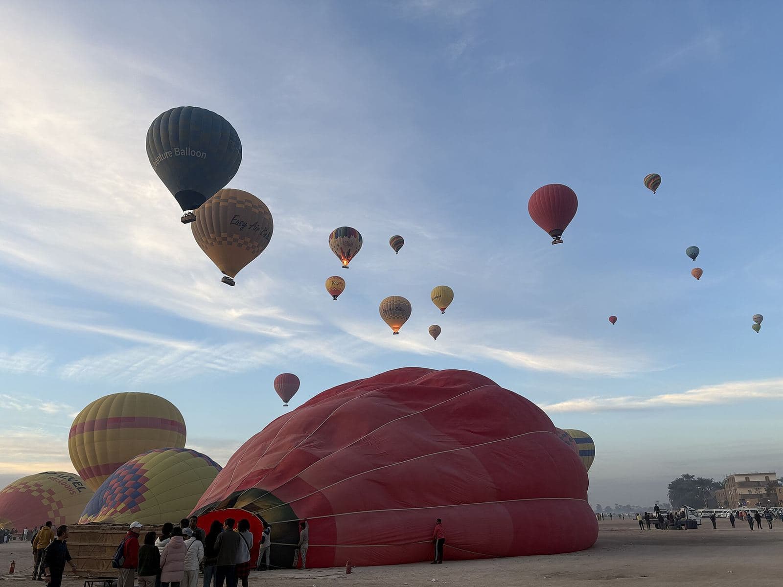 Hot air balloons inflating and launching at sunrise in Luxor